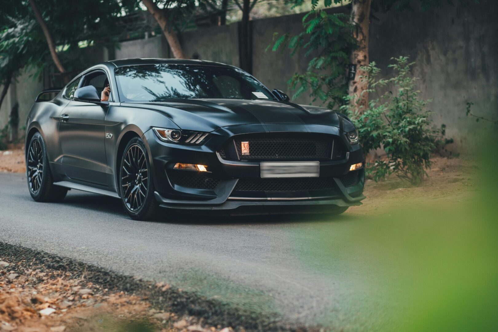gt mustang A black car is driving down the street